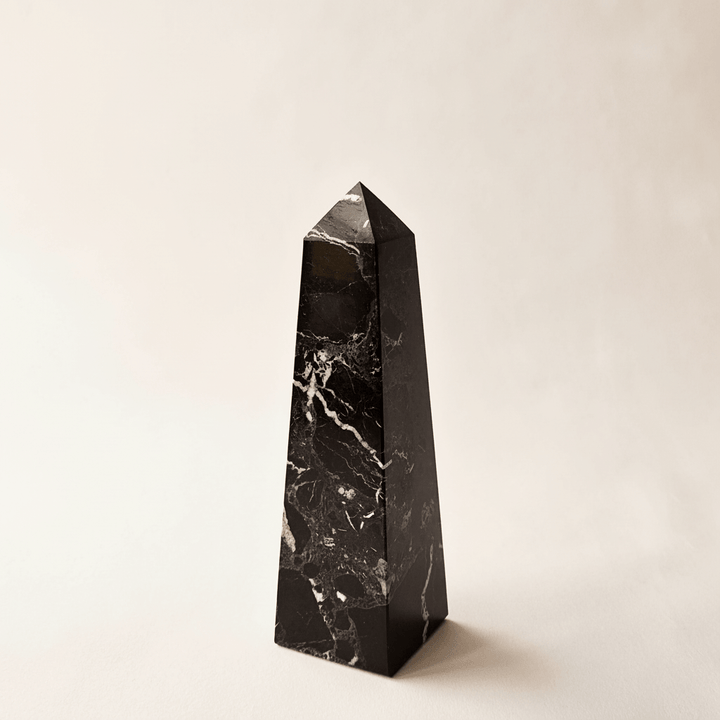 Black marble obelisk on a beige background
