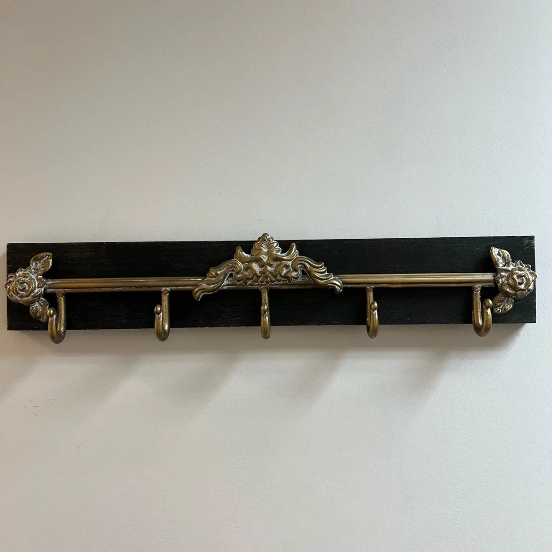 Front view of the black wall rack with antique gold ornament