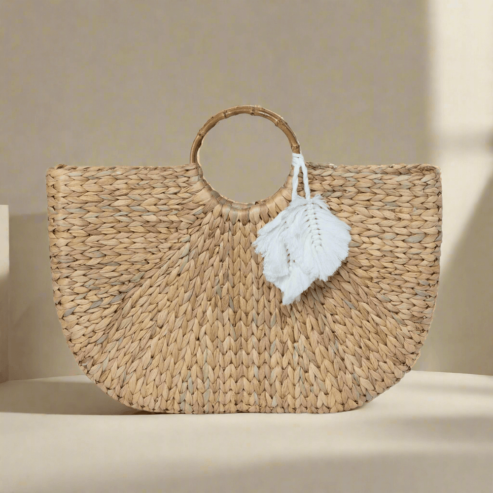 Handwoven boho chic straw tote bag with white tassels and circular handles, showcasing artisanal craftsmanship and natural style.