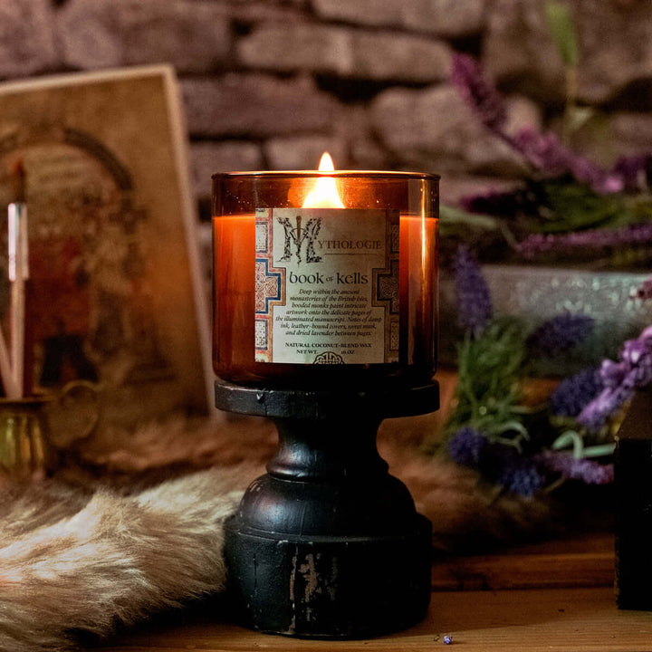 Book of Kells Candle on a wooden stand with lavender and ancient manuscript decor.