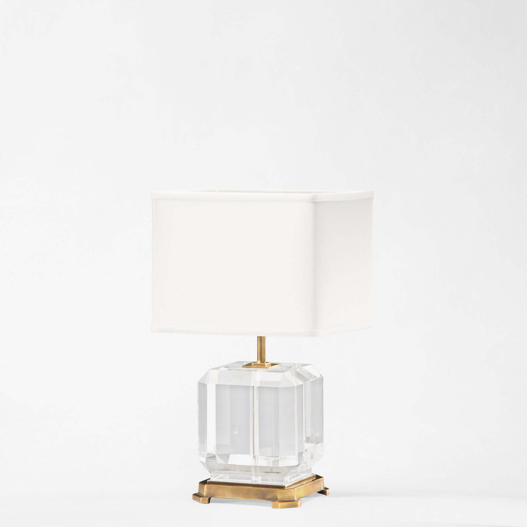 Clear glass table lamp with gold base on a white background