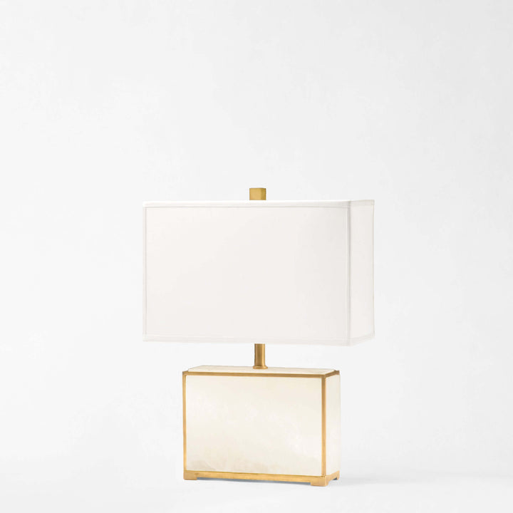 Table lamp with gold frame and white shade on a light gray background