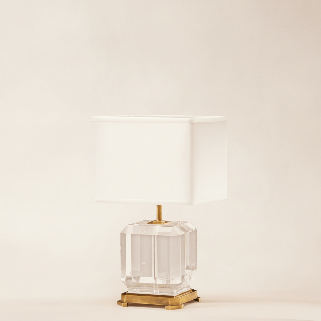 Decorative table lamp with a clear glass base and gold accents on a beige background