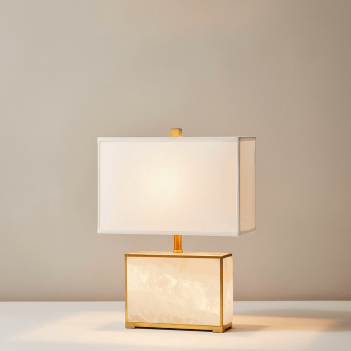 Table lamp with gold base and white shade on a neutral background