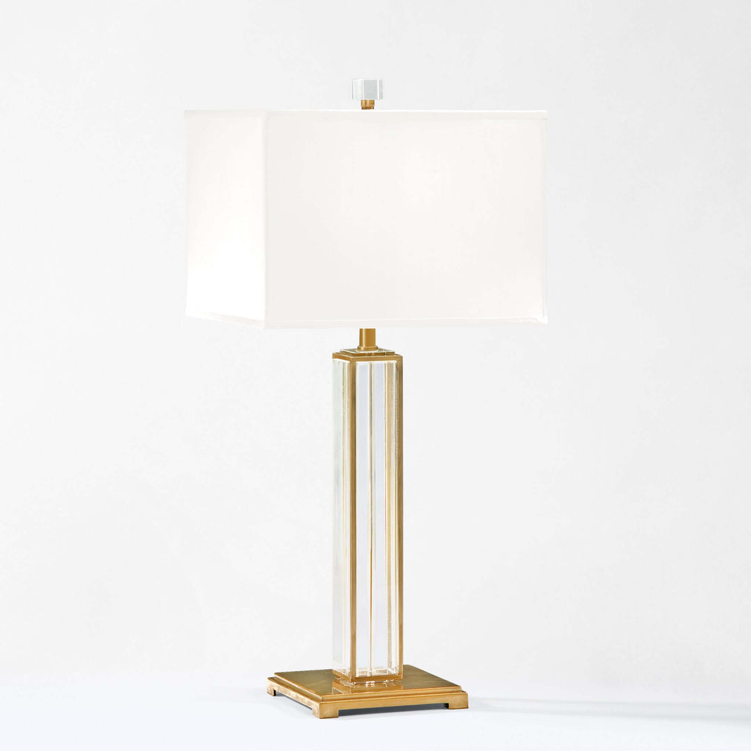 Tall table lamp with gold base and white shade on a white background