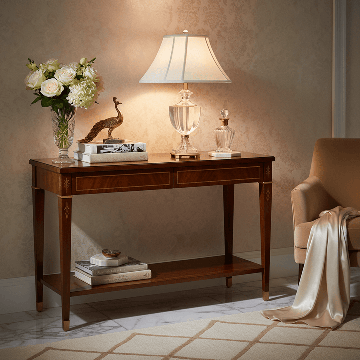 Table lamp on wooden console table with decorative items against a beige wall