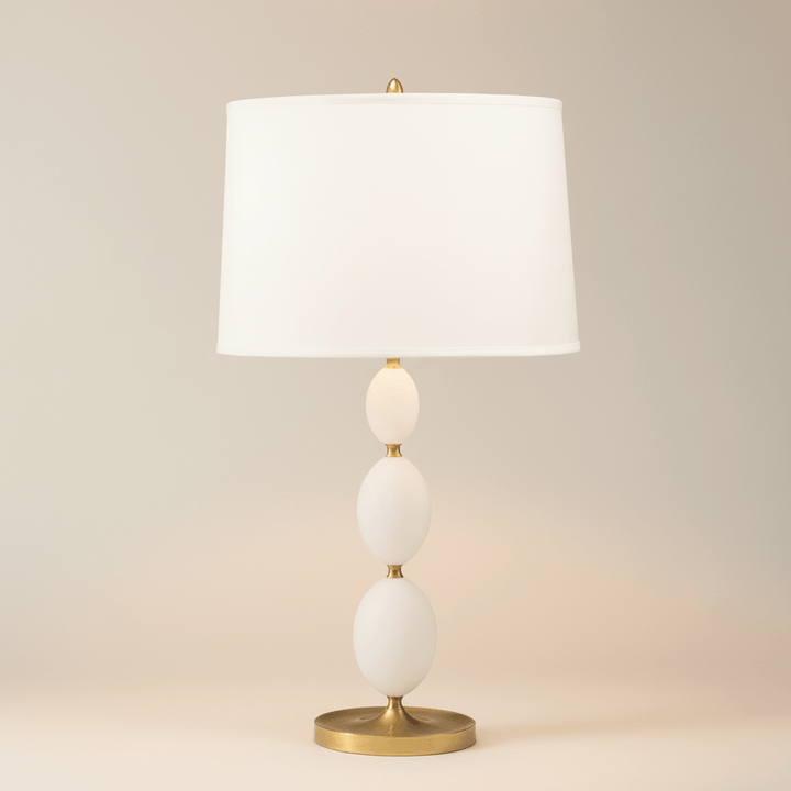Table lamp with white shade and gold base on a beige background