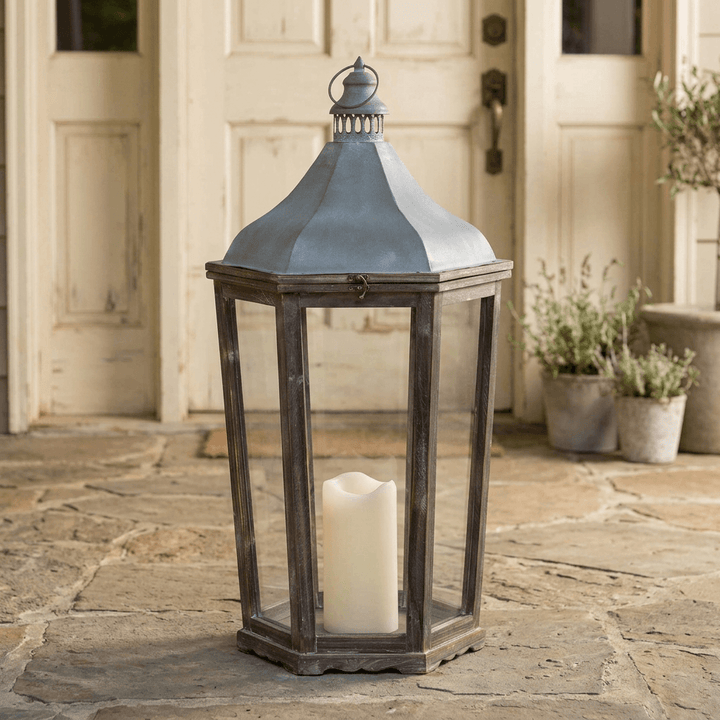 Large Briarwick Carriage Lantern with an ivory pillar candle at a sheltered cream doorway