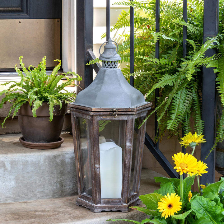 Briarwick Carriage Lantern, medium: lantern styled with a white candle on a sheltered porch