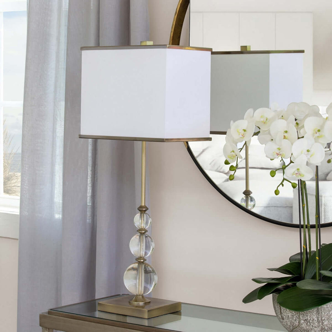 Buffet Lamp with Crystal Orbs and Brass Base on a mirrored console with elegant decor and an orchid