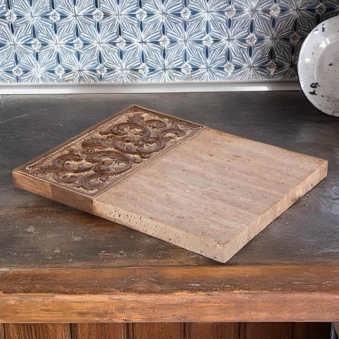 Carved wood and marble cutting board with ornate detail, featuring rustic charm and cool elegance, displayed on a kitchen counter.
