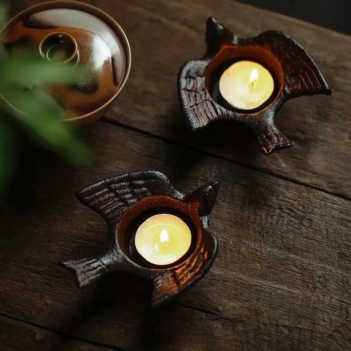Two cast iron bird tea light holders with lit candles