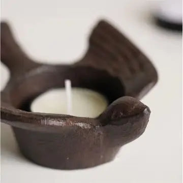Side view of cast iron bird tea light holder with a small candle