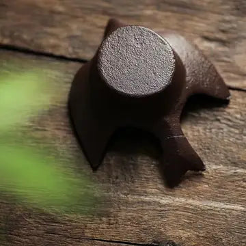 Underside of cast iron bird tea light holder on a wooden surface
