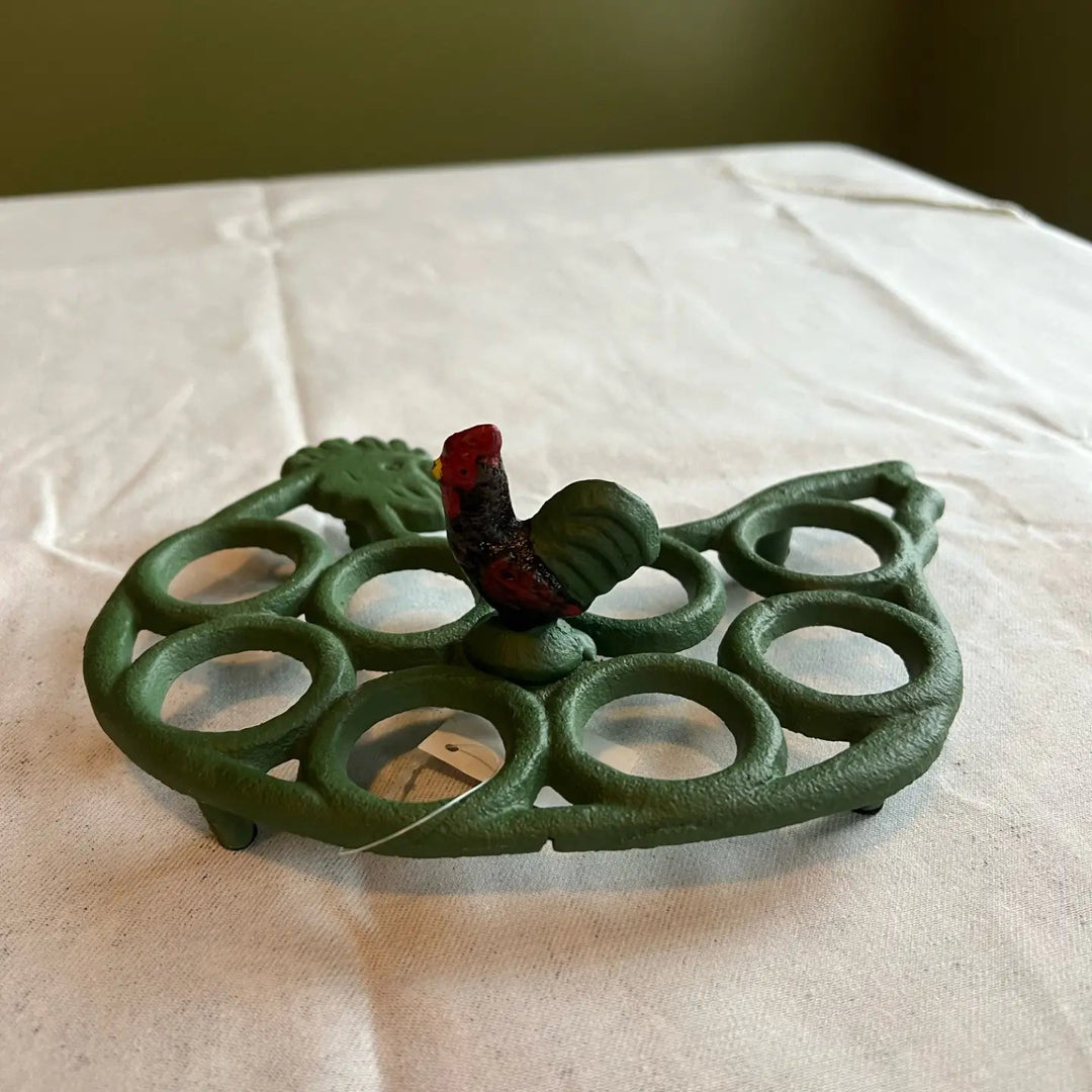 Empty dark green egg rack showing eight rings and a central rooster