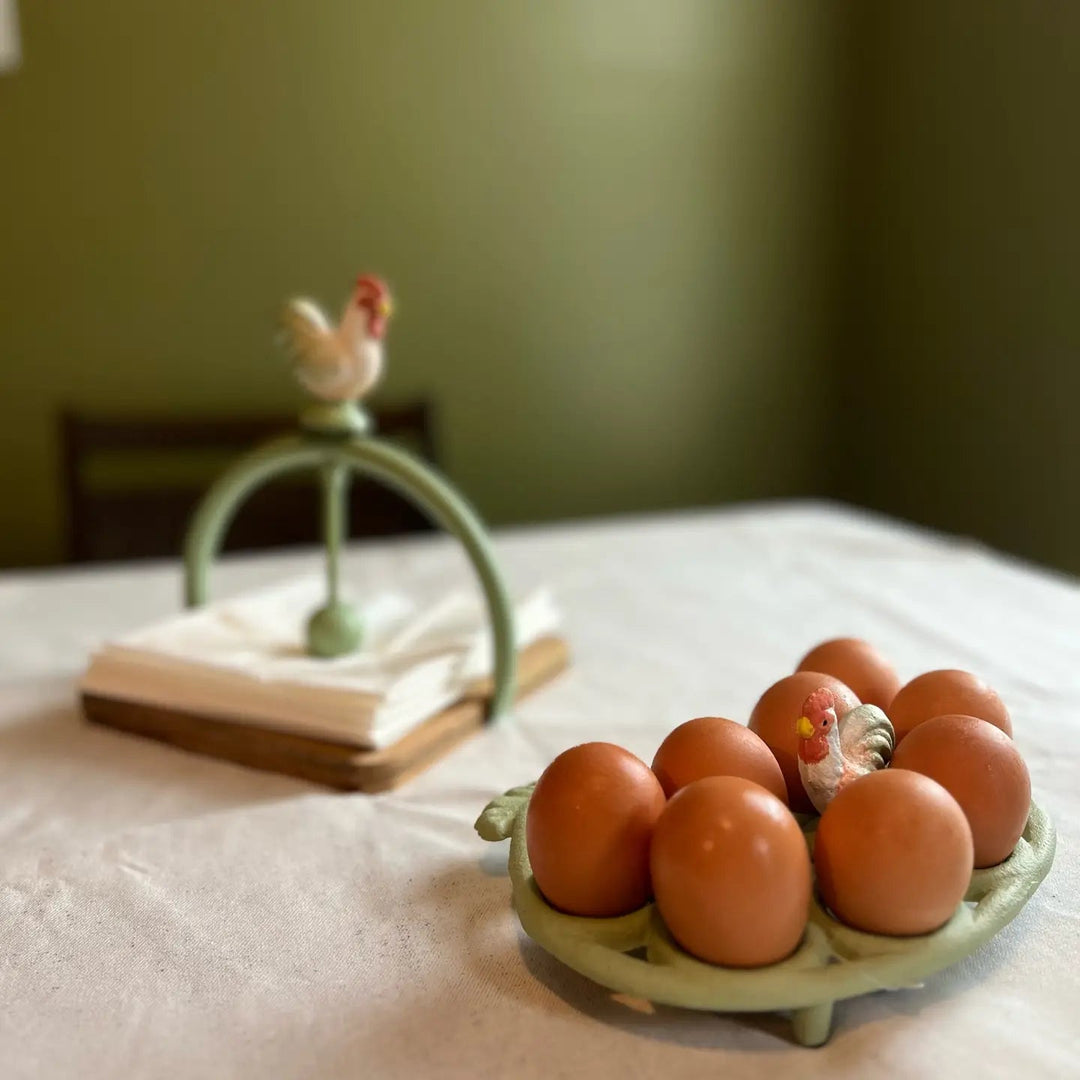 Light green egg rack with eggs beside a separate napkin holder