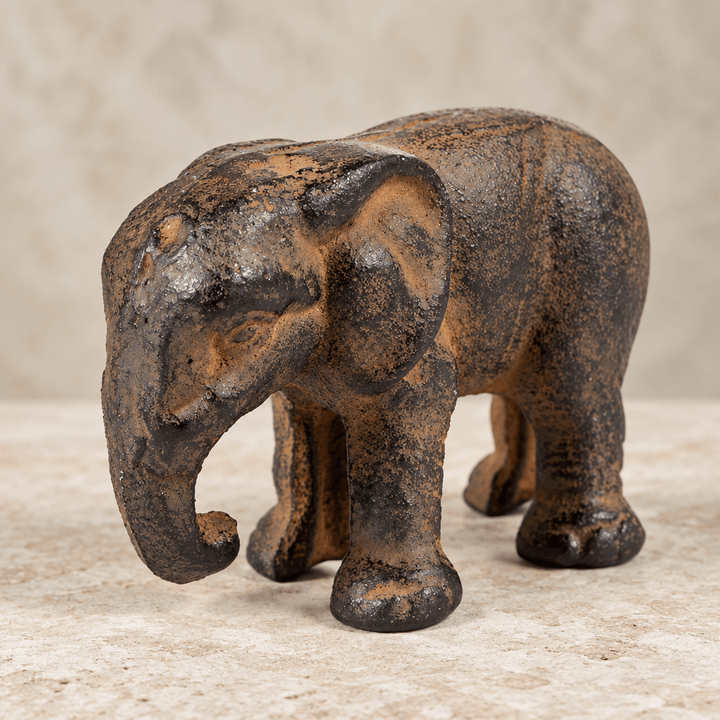 Close view of a cast iron elephant figurine showing its textured brown-black surface on pale stone.