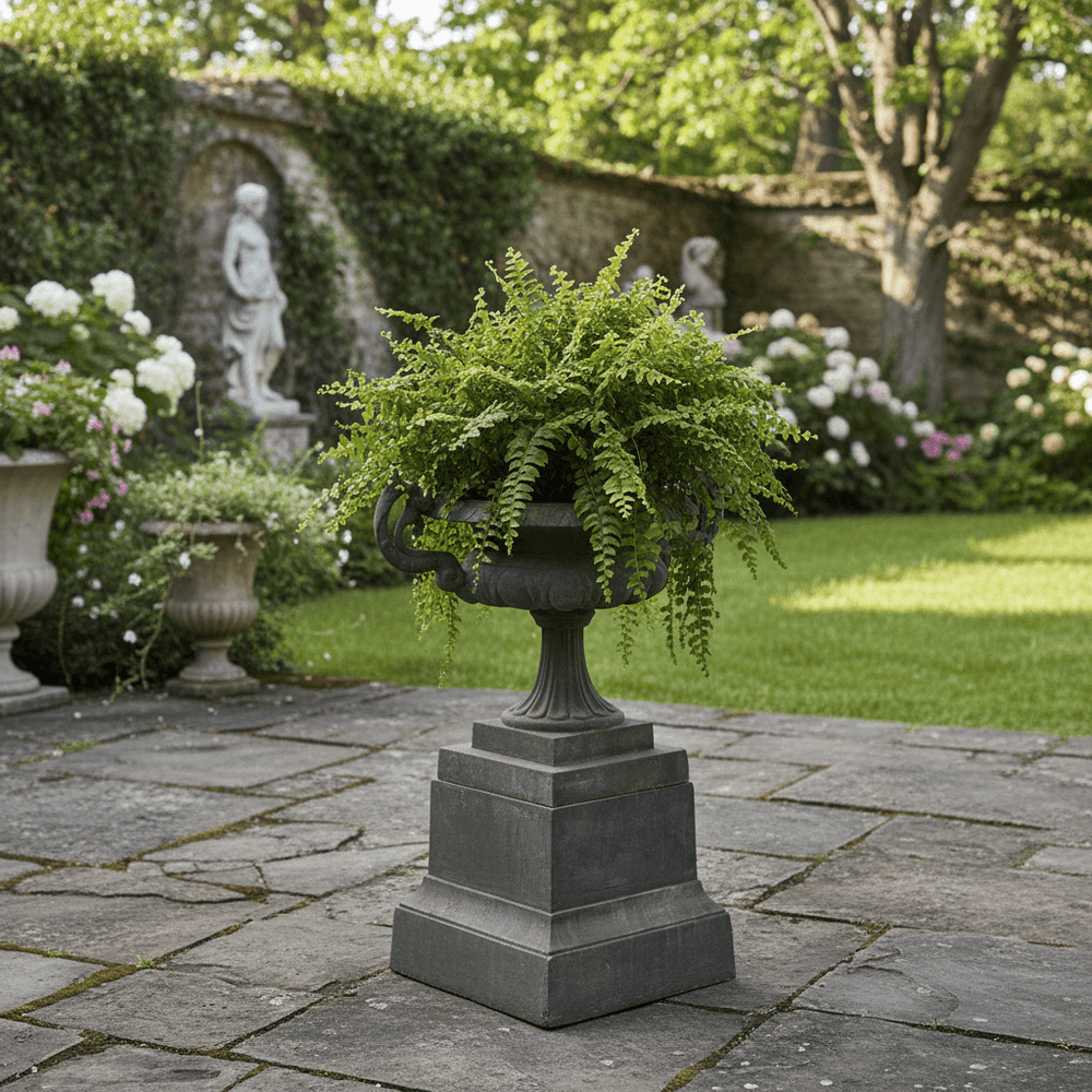 Cast Iron Garden Urn on Plinth with Scroll Handles in a classical garden setting.