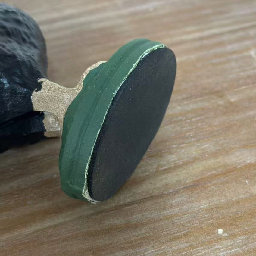 Black protective pad beneath the green rooster figurine base