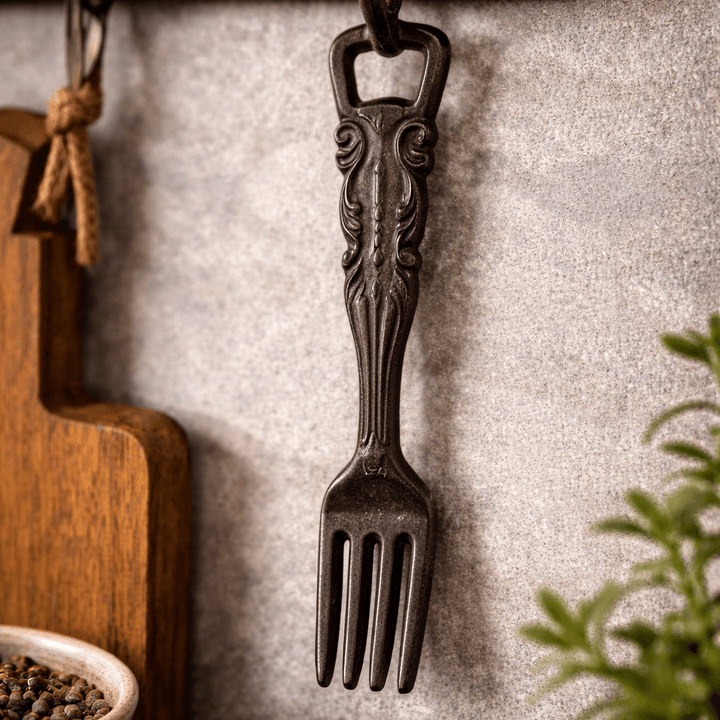Ornate cast iron fork bottle opener hanging beside a wood serving board