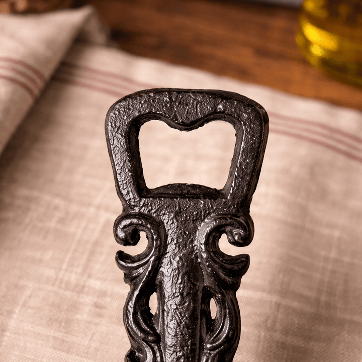 Close view of the textured opener end and scrollwork on the cast iron utensil bottle opener