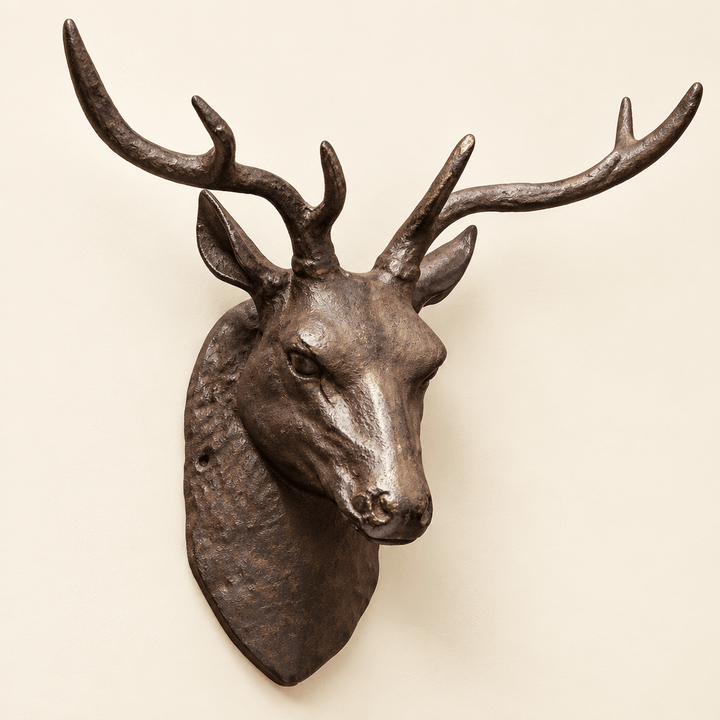 Dark cast iron stag head with sculpted antlers mounted on an ivory wall
