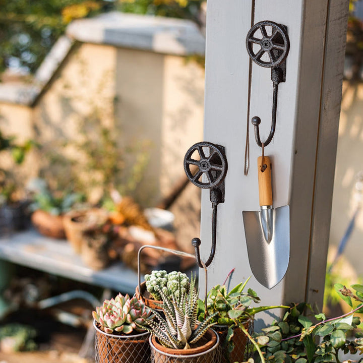 Pair of Cast Iron Valve Wheel Wall Hooks holding garden tools