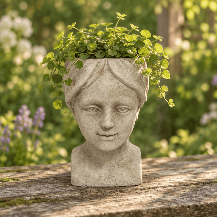 Cement Girl Head Planter with greenery on a wooden garden table