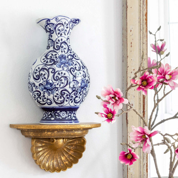 Chinoiserie Blue and White Floral Porcelain Vase on a gold wall shelf with pink blossoms nearby, enhancing traditional decor.