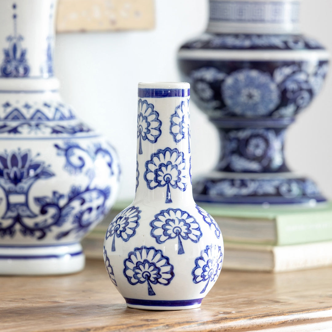 Chinoiserie Blue and White Porcelain Bud Vase (Set of 2) displayed on a wooden table with decorative background vases.