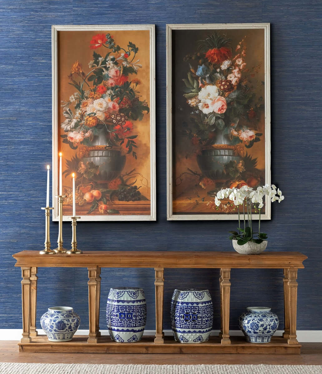 Elegant room with Chinoiserie porcelain garden stools, floral paintings, and a wooden console table with candles and orchid decor.