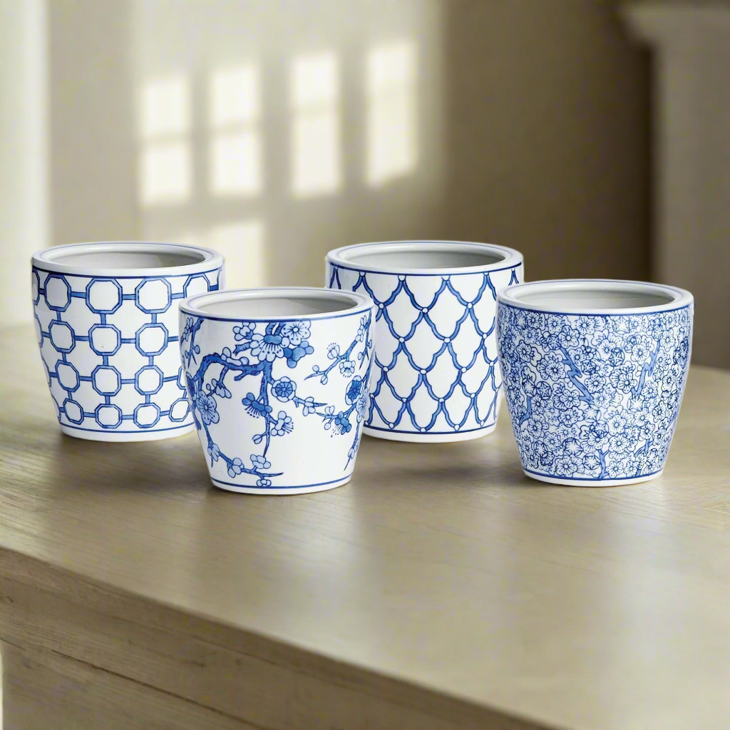 Set of four chinoiserie blue and white ceramic pots with floral and geometric patterns on a wooden table.