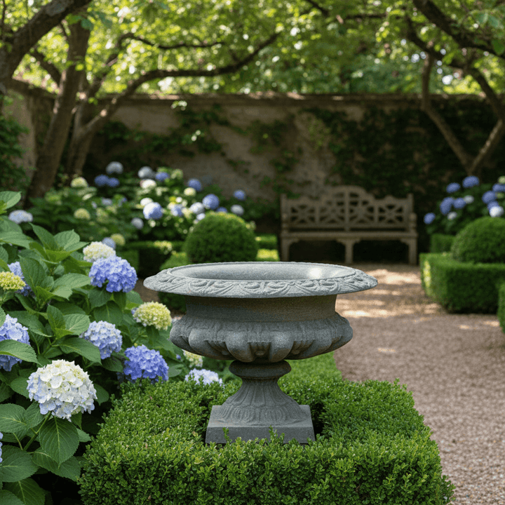 Classic Cast Iron Garden Urn with Weathered Patina Finish in elegant garden setting