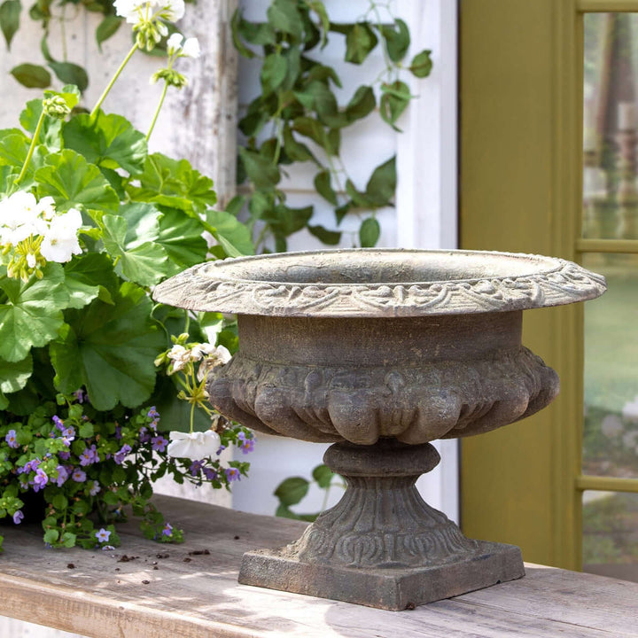 Classic Cast Iron Garden Urn with Weathered Patina Finish on rustic outdoor table