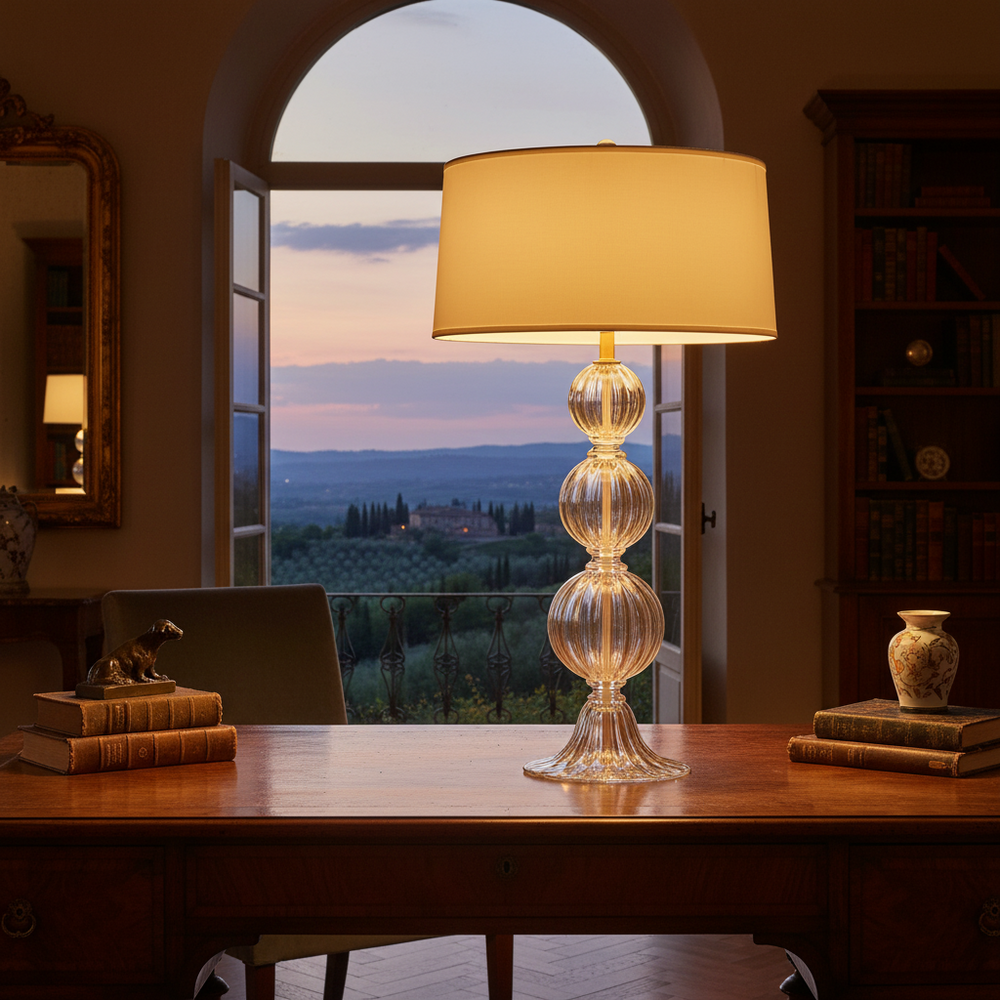 Decorative glass table lamp on a wooden desk with a scenic view through a window.