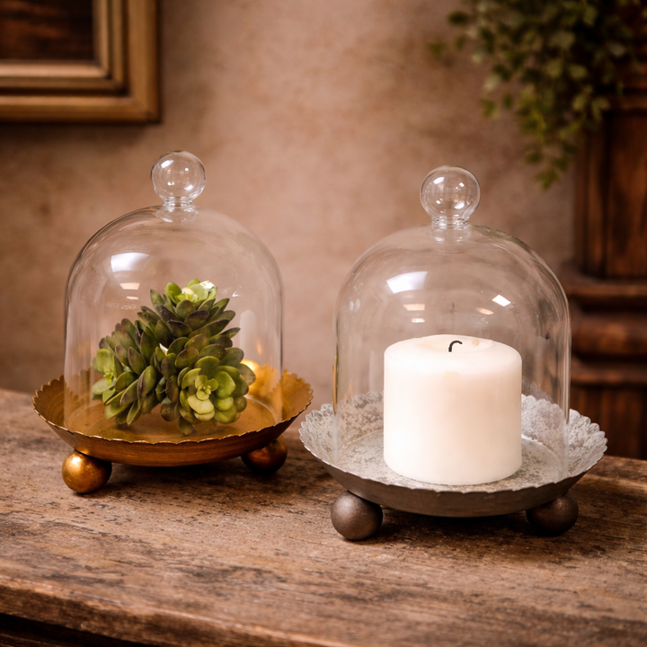 Clear glass cloche lifted above the gold candle plate