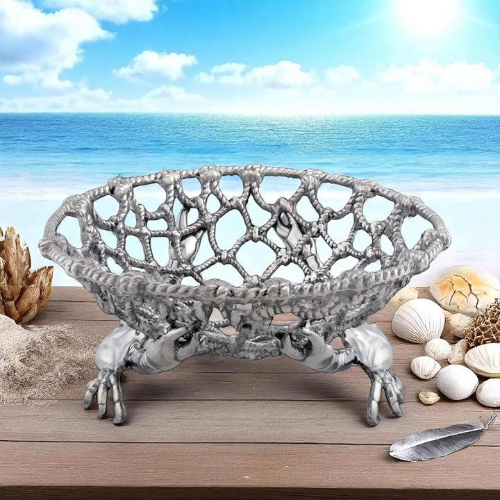 Coastal Crab and Net Fruit Basket displayed on a wooden table with a seaside background, featuring handcrafted aluminum design.