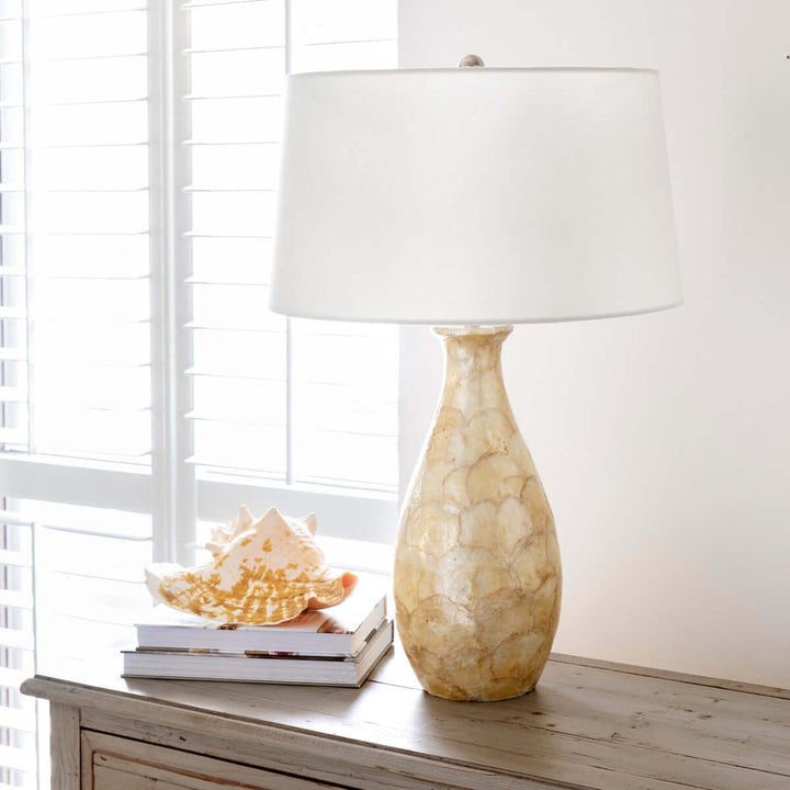 Coastal Pearl Capiz Shell Table Lamp with Linen Shade on wooden dresser by window.