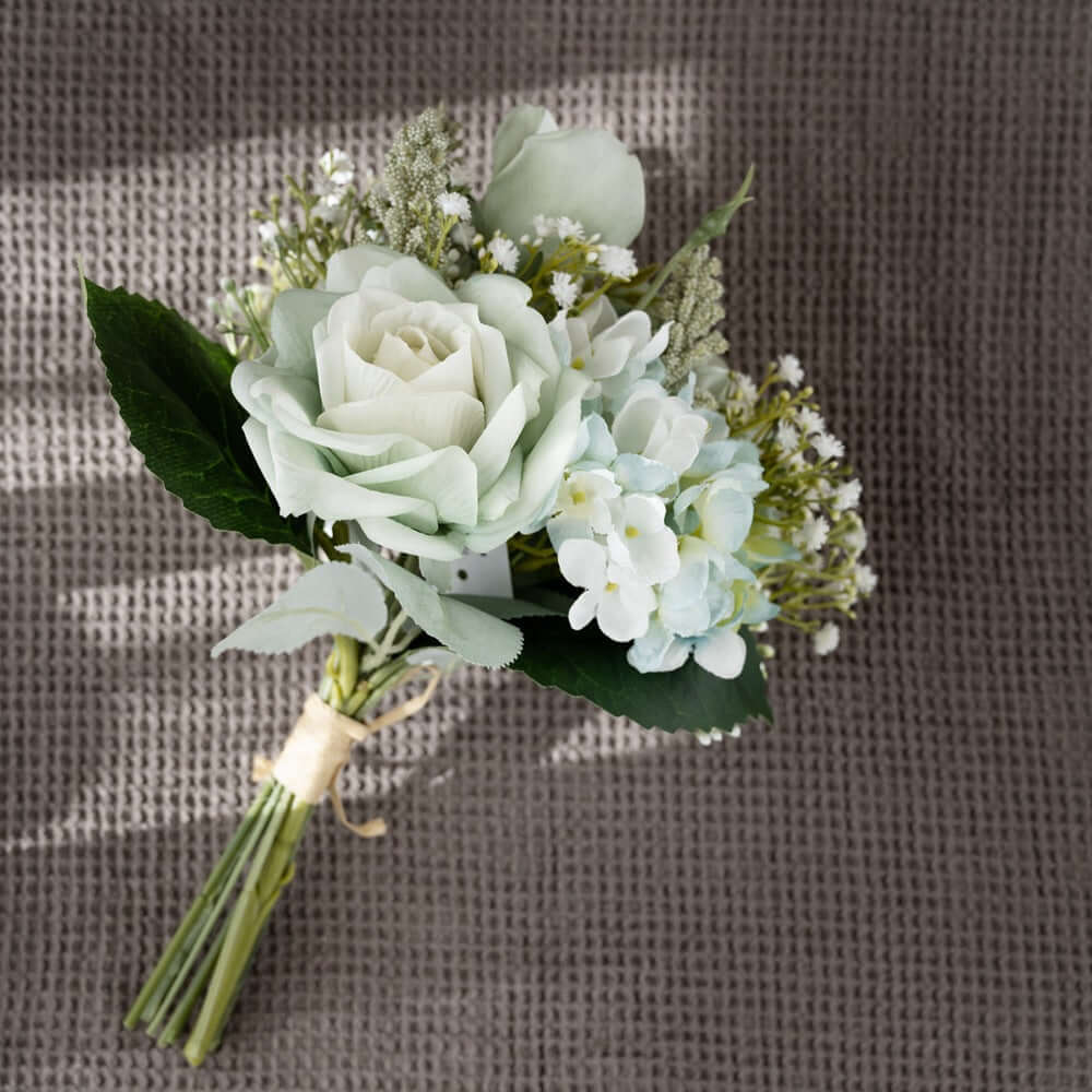 Cottagecore artificial floral arrangement with white roses and wildflowers on a textured background.