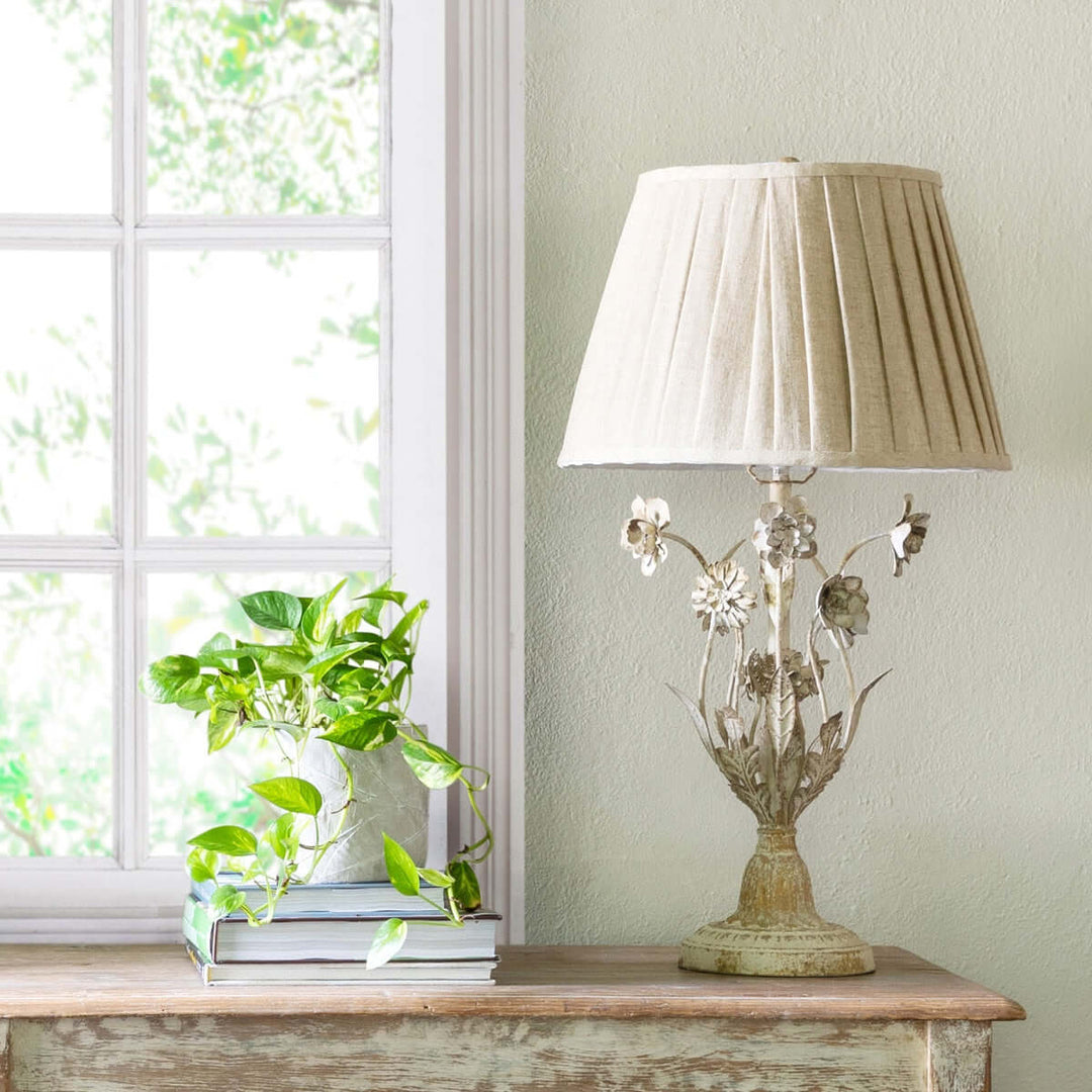 Cottagecore table lamp with vintage floral details on a rustic wooden table by a window, exuding countryside charm and romance.