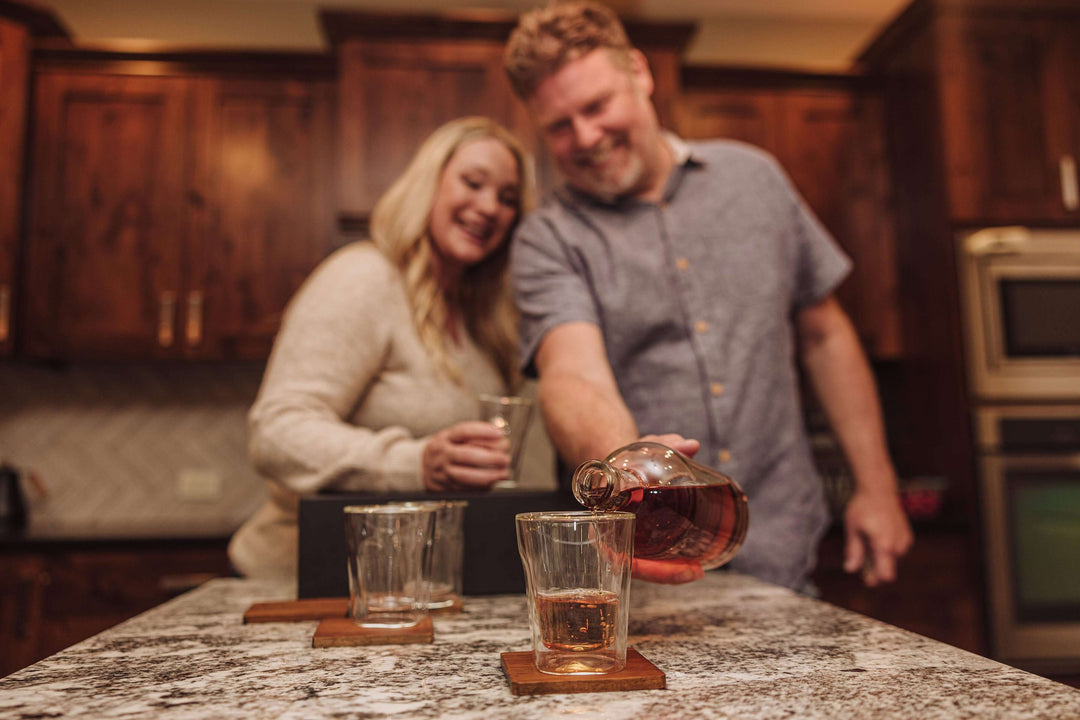 Couple enjoying whiskey from the Old World Whiskey Decanter and Glass Set in Faux Leather Case, adding elegance to a cozy evening.