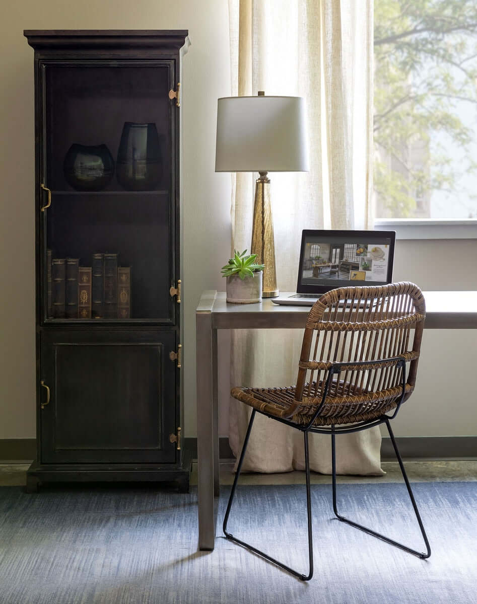 Modern office with crackled glass table lamp and white linen shade, wooden desk, and wicker chair by a window.