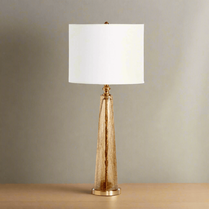 Crackled glass table lamp with white linen shade on wooden table showcasing elegant design and artistic craftsmanship.