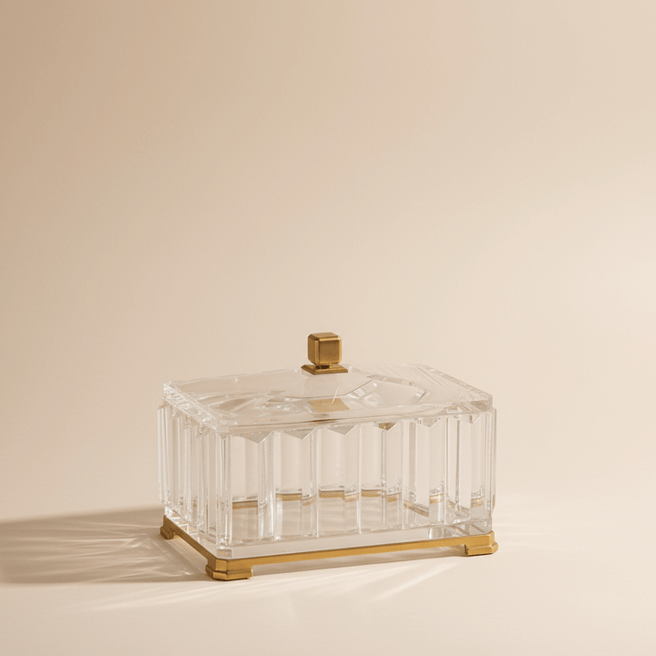 Clear glass box with gold accents on a beige background