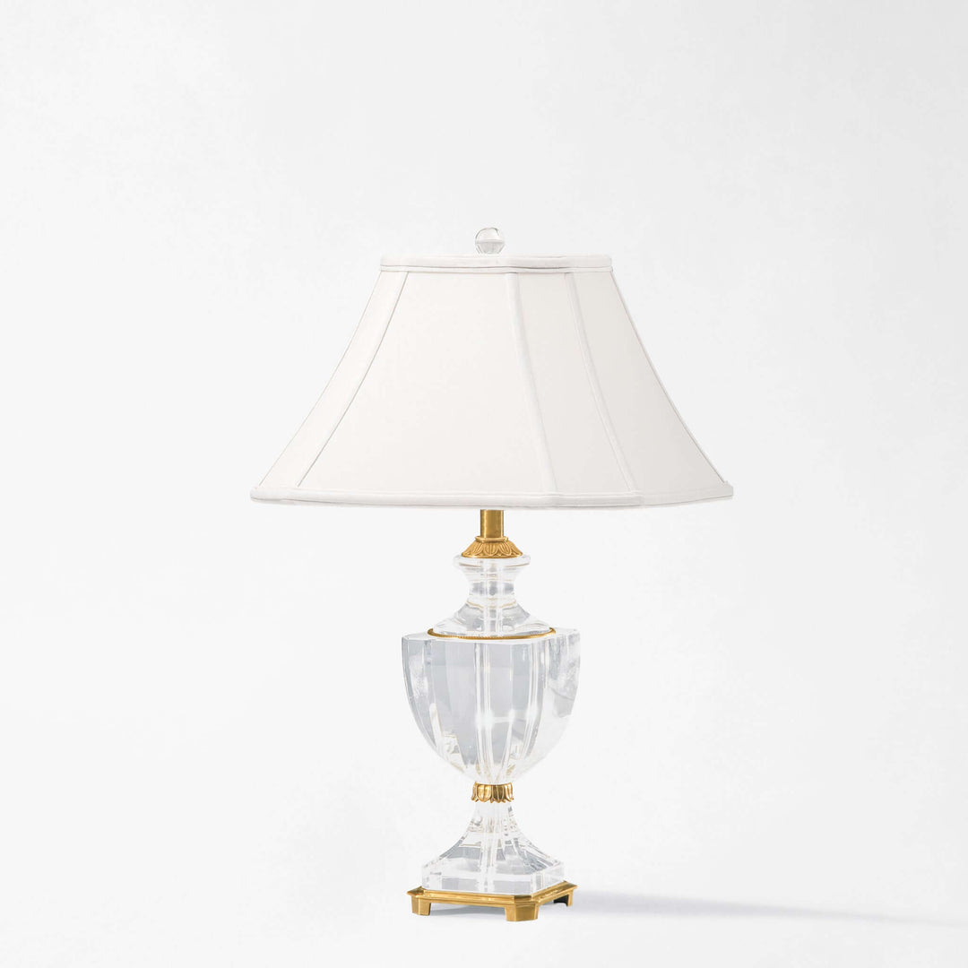 Decorative lamp with a clear crystal glass base and white shade on a white background