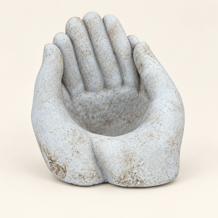 Weathered cement cupped-hands planter on an ivory studio background