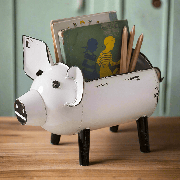 Rustic pig-shaped storage organizer in distressed white finish, holding books and pencils on a wooden table.