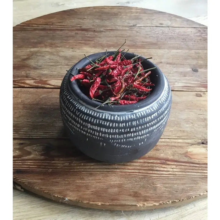 Textured dark glaze planter filled with dried red peppers on a rustic table