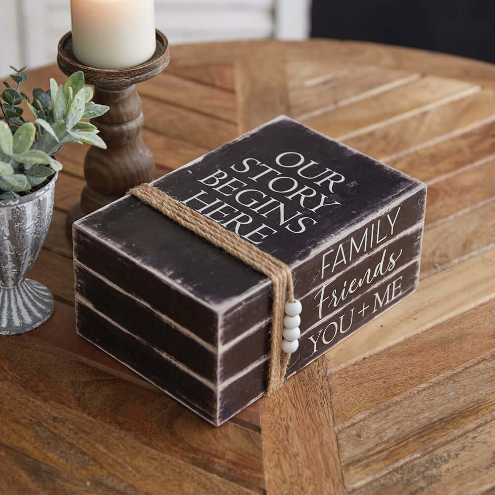Decorative Vintage Faux Book Stack on wooden table with candle and plant