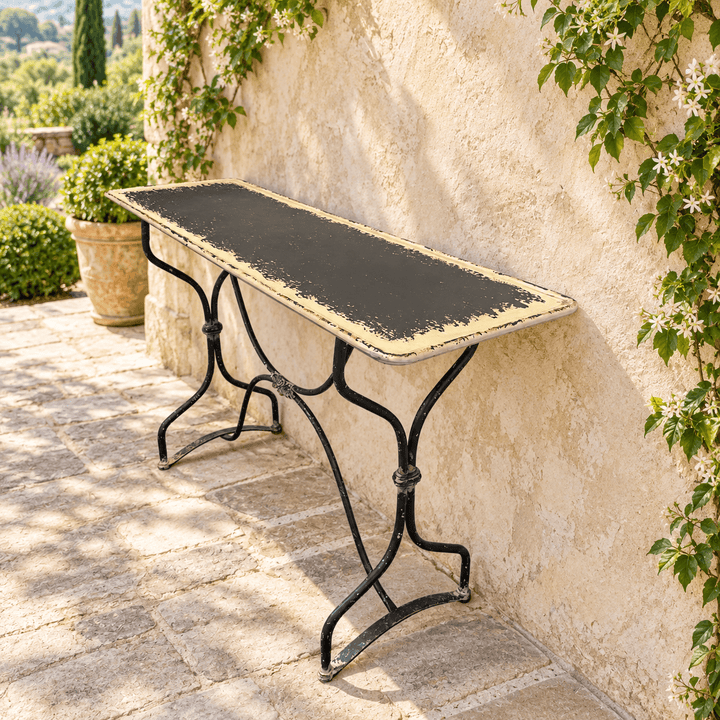 Distressed Black and Cream Metal Console Table against a sunlit stucco wall